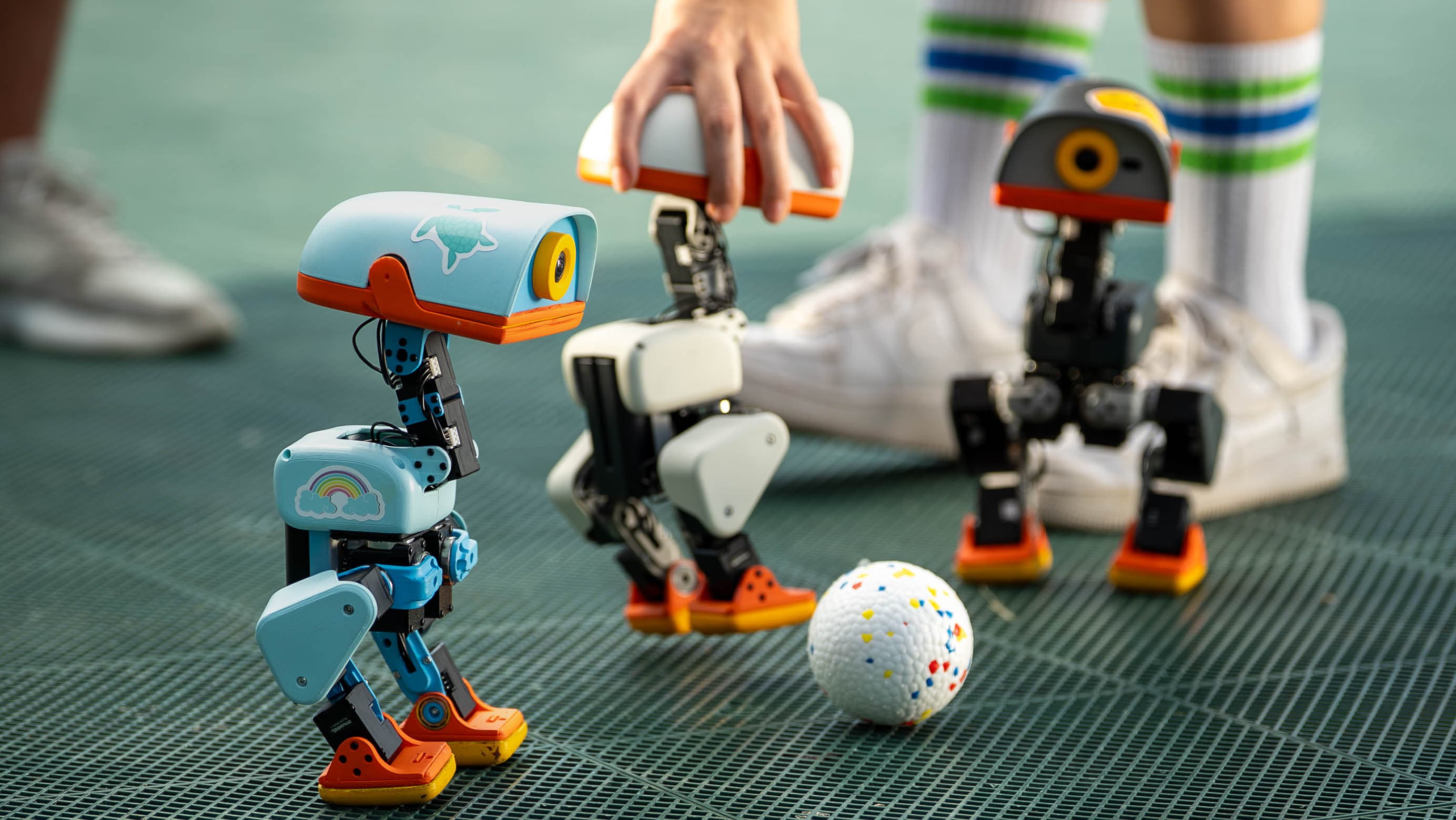 Three Microduck robots gathered around a small ball
